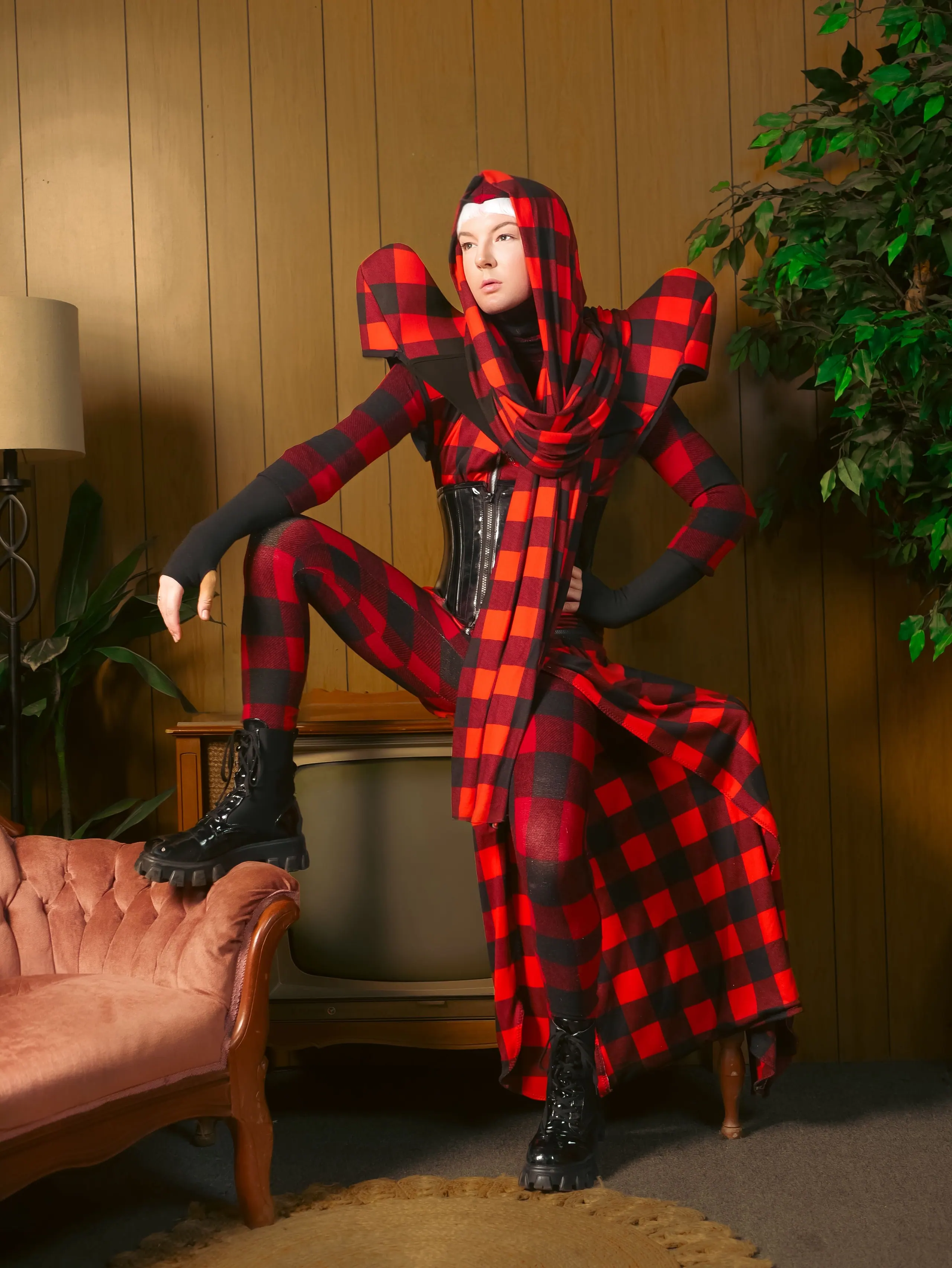 The buffalo check look standing with one boot on a vintage sofa in a wood-panelled room